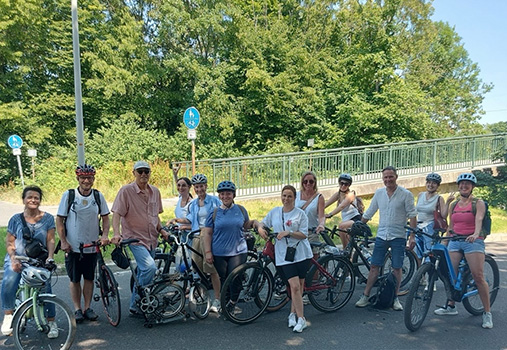 Mitarbeiterinnen und Mitarbeiter der Praxis machen bei einem gemeinsamen Fahrradausflug eine Pause für ein Gruppenfoto.