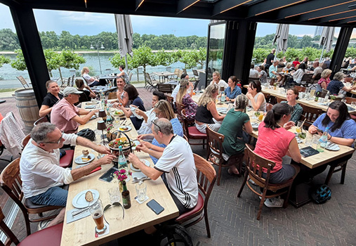 Gemeinsame Einkehr des Praxisteams während des Fahrradausflugs in einem Restaurant mit Blick aufs Wasser.